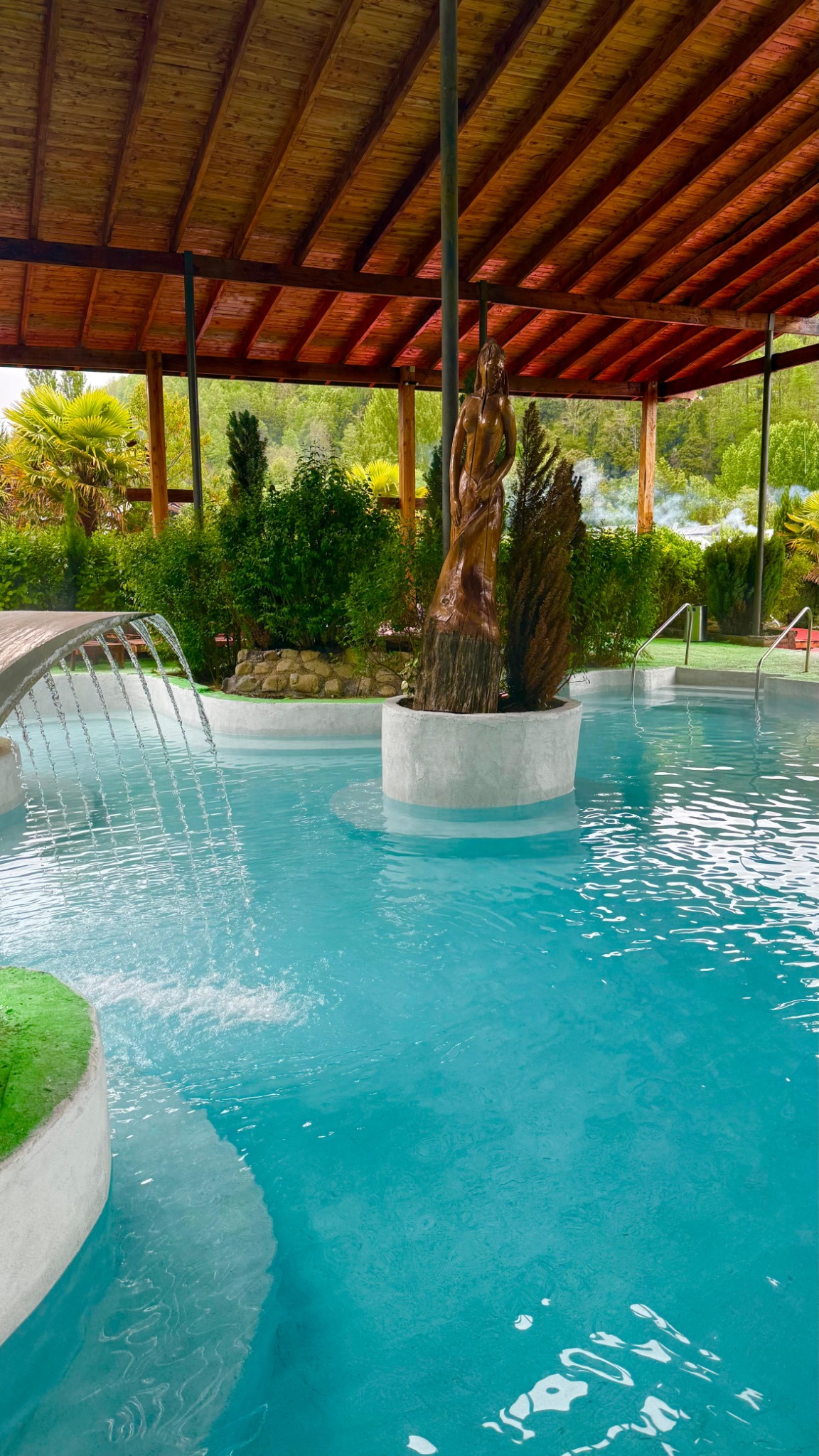 Piscina techada con cascada y entorno de vegetación